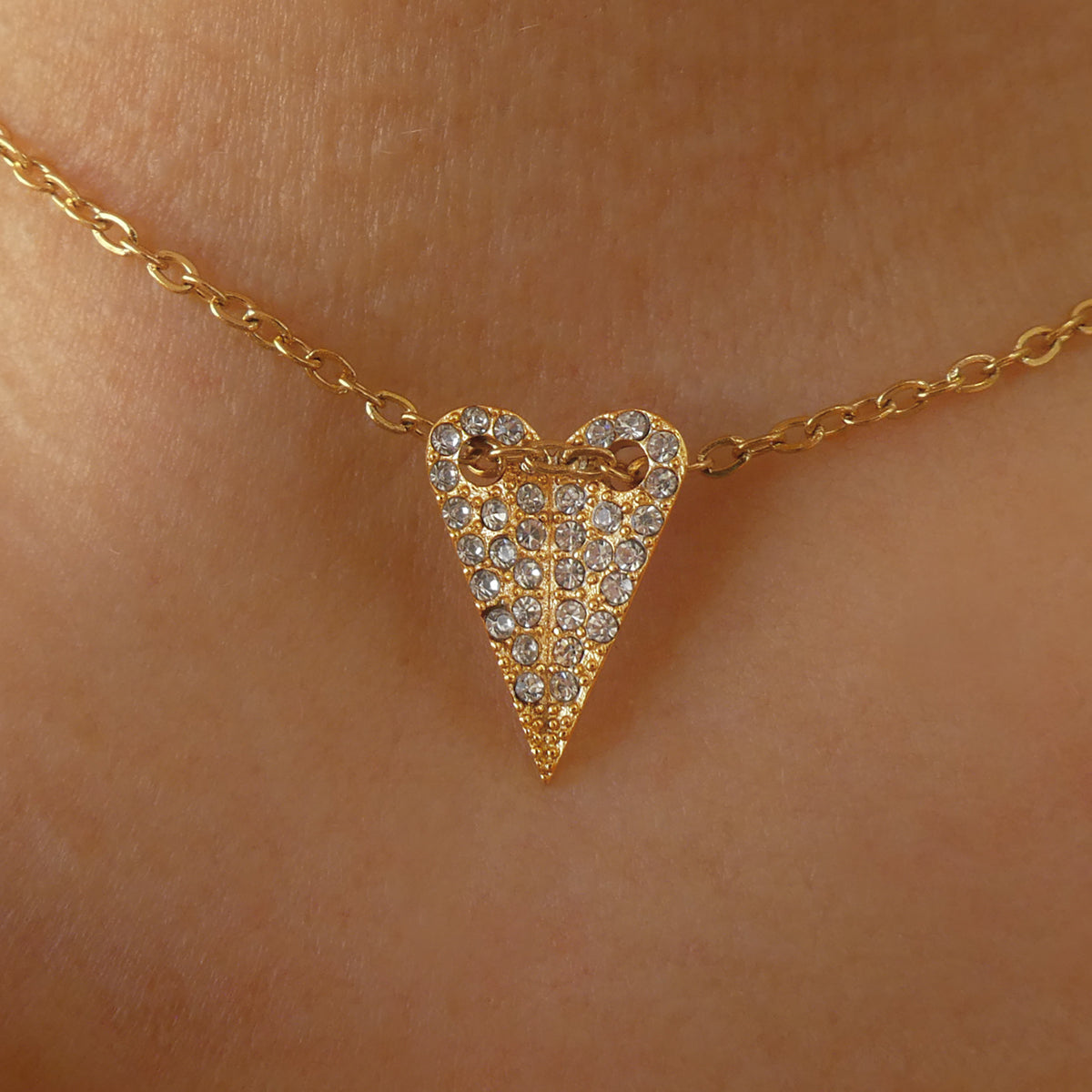 Gold heart pendant necklace by AN JEWELS JEWELRY Mod. AL.NMOH24CZ on skin, sparkling with embedded stones