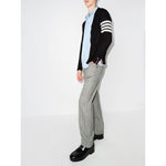 Model wearing Thom Browne Sweaters Blue, navy wool cardigan with 4-Bar stripe and button fastening, paired with grey pants and black shoes.