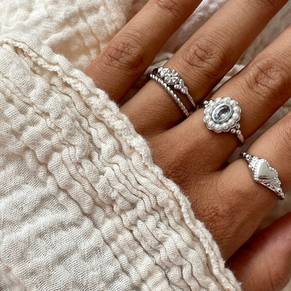 Hand wearing 24KAE JEWELS JEWELRY Mod. 12416S/56 silver rings with intricate detailing on fingers, wrapped in textured fabric.