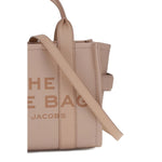 Close-up of Marc Jacobs The Small Tote Handbag in beige leather, featuring sturdy design with tubular handles and adjustable strap.