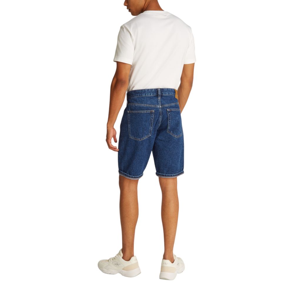 Back view of a model wearing Calvin Klein Jeans Blue Cotton Bermuda Shorts with white sneakers and a white t-shirt.