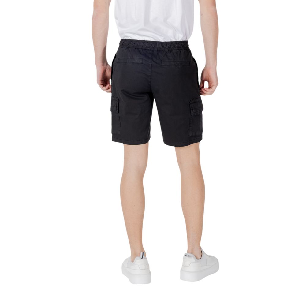 Back view of a man wearing Hugo Boss Black Cotton Bermuda Shorts with white sneakers on a white background
