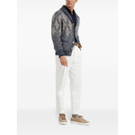 Man wearing patterned blue cardigan with white pants and beige sneakers.