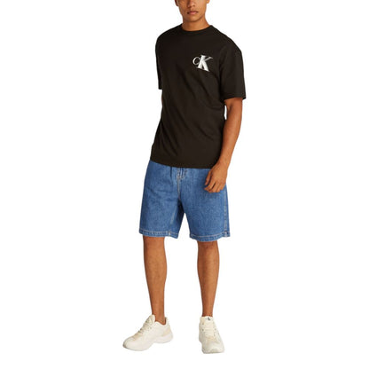 Man wearing Calvin Klein Jeans Blue Cotton Bermuda Shorts with a black t-shirt and white sneakers.