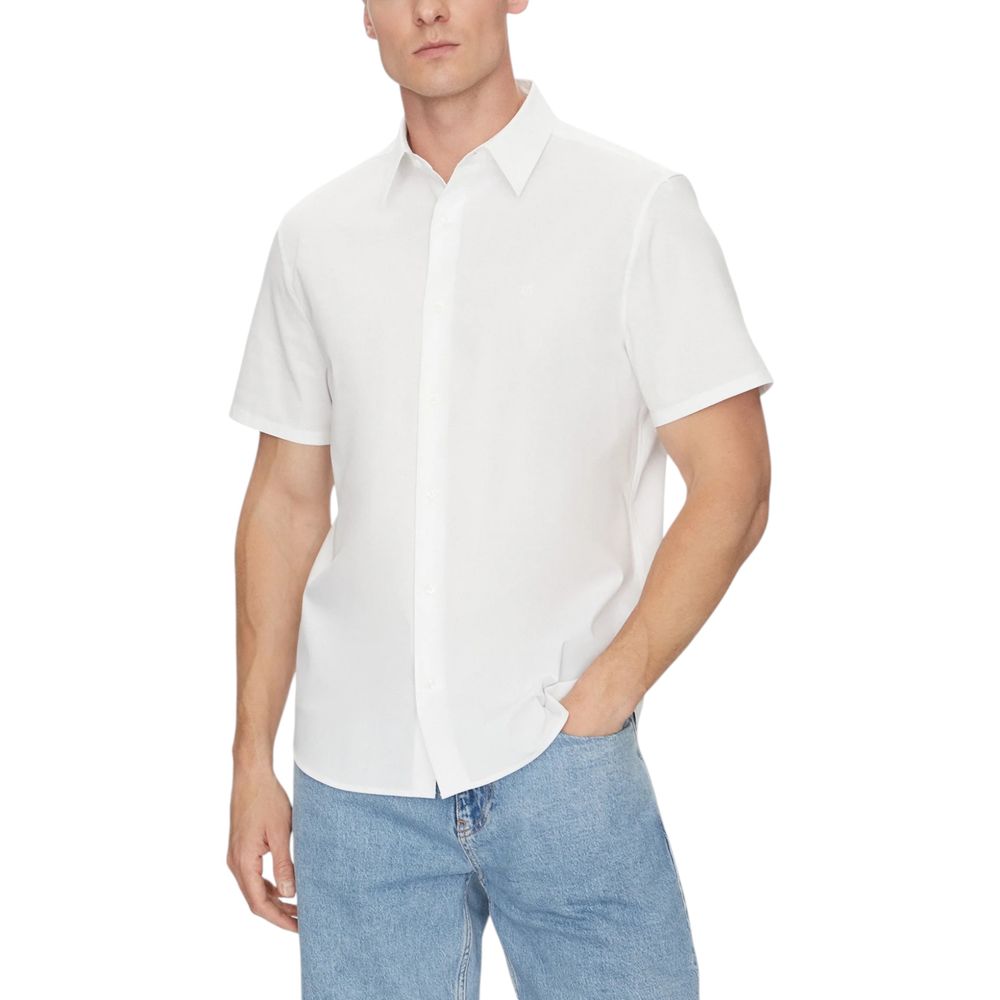 Man wearing Calvin Klein White Organic Cotton Shortsleeve Shirt with blue jeans, showcasing minimalist summer style.