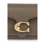 Close-up of Coach Tabby 20 shoulder bag with gold-tone clasp detail on brown leather exterior.