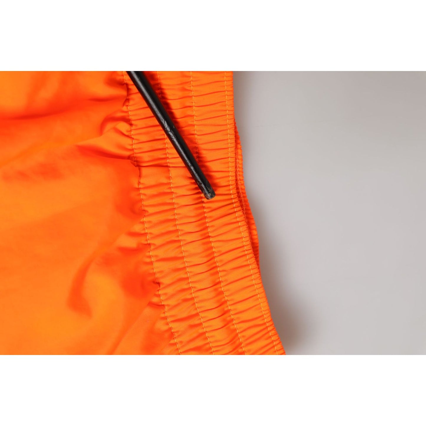 Close-up of Dolce & Gabbana Orange Polyester Beachwear Men Shorts Swimwear with drawstring waistband and zipper detail.