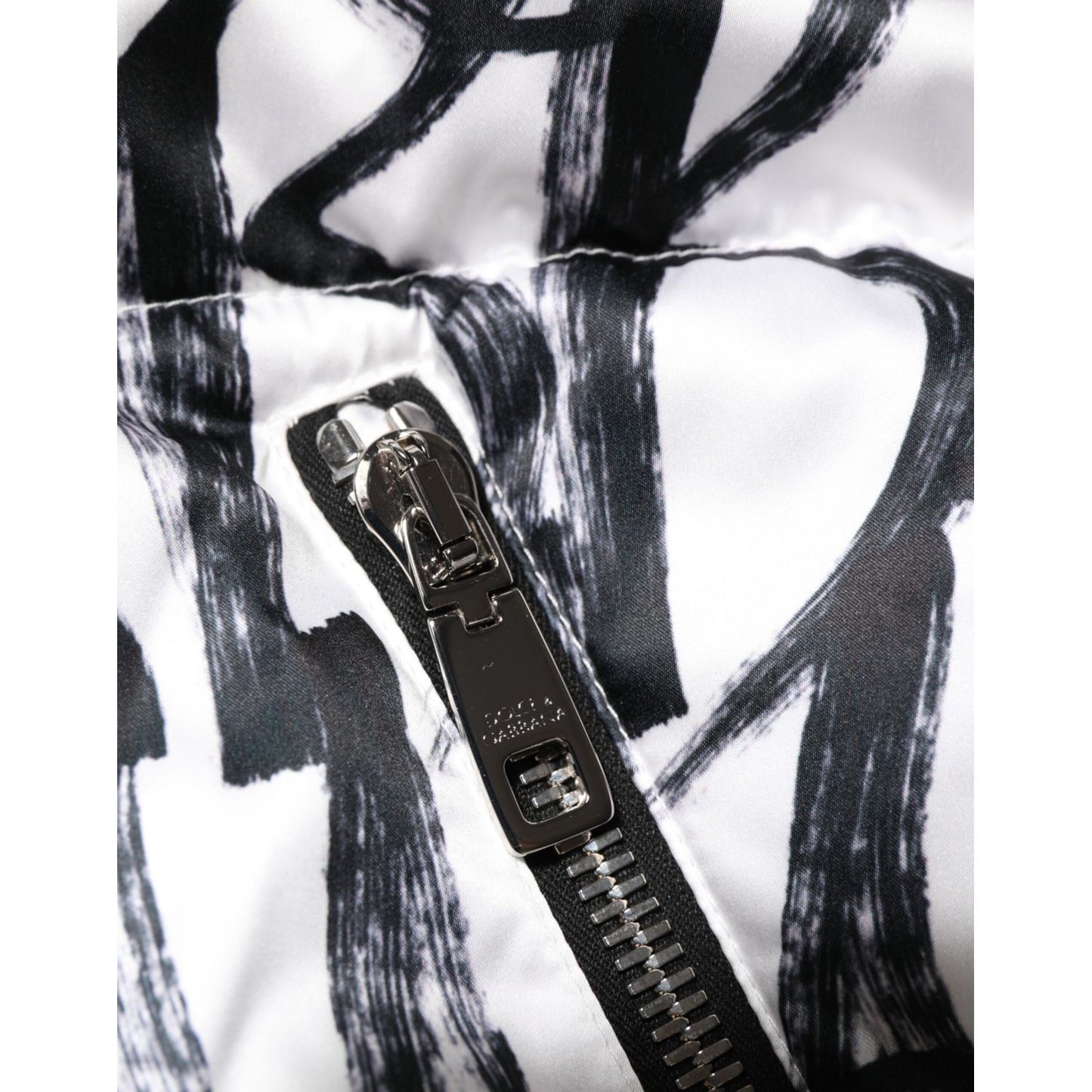 Close-up of Dolce & Gabbana White Black Graffiti Logo Puffer Bomber Jacket zipper detail with bold graffiti print.