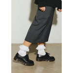 Woman wearing Dr. Martens White Polyester Sock with black shoes and gray pants.