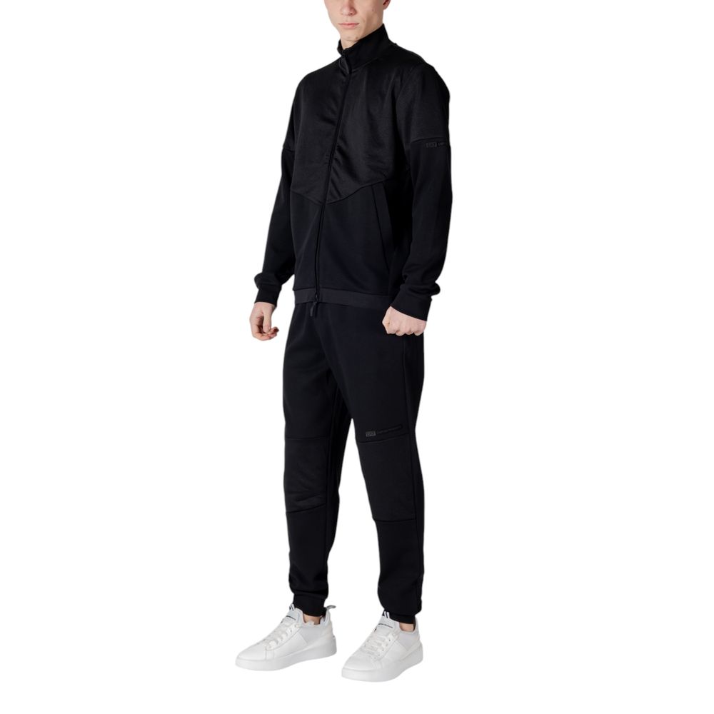 Man wearing EA7 Emporio Armani Black Cotton Sweatsuit with white sneakers, showcasing a modern and sporty look.