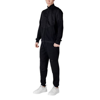Man wearing EA7 Emporio Armani Black Cotton Sweatsuit with white sneakers, showcasing a modern and sporty look.
