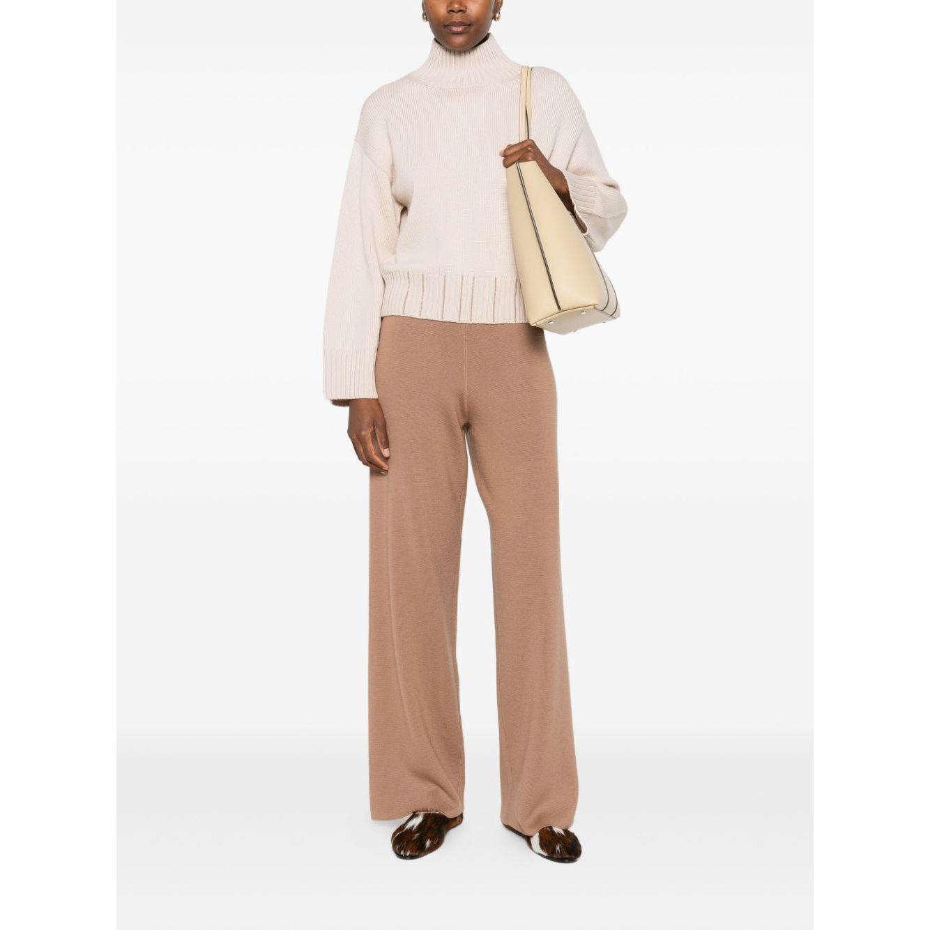 Woman wearing Fabiana Filippi Sweaters Powder, a light beige high neck ribbed knit with long sleeves, paired with tan pants.