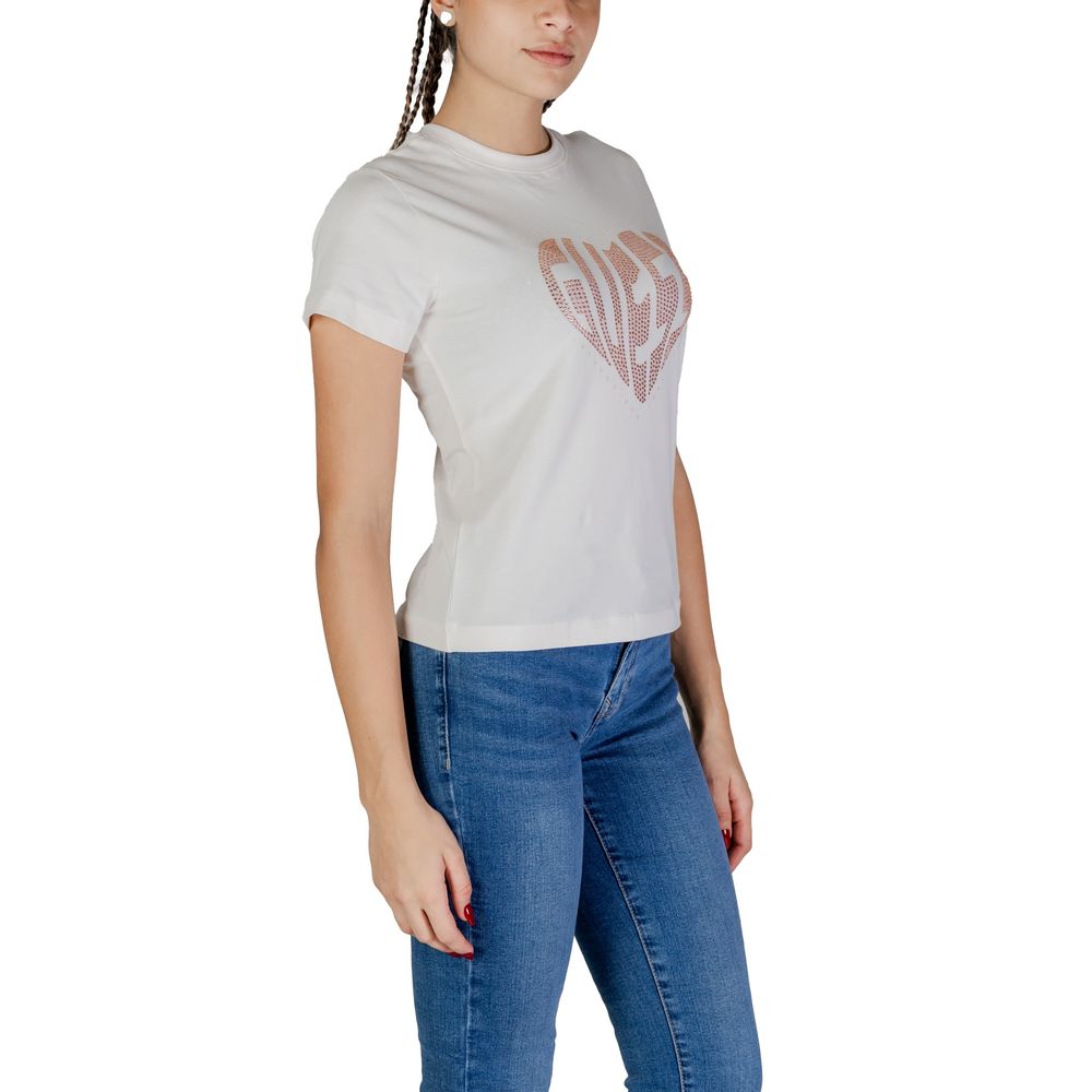 Woman wearing Guess Active Cream Cotton T-Shirt with rhinestone logo, paired with jeans, showcasing comfortable and stylish fit.