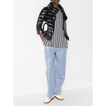 Model wearing Herno Jackets Black, Sofia nylon cape, paired with a striped shirt and blue pants.