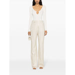 Woman wearing JACQUEMUS Top White with ribbed knit and cut-out detailing, paired with beige trousers and holding a small bag.