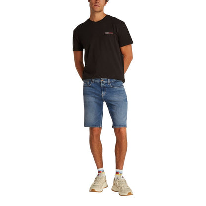 Man wearing Tommy Hilfiger Jeans Blue Recycled Cotton Bermuda Shorts, black t-shirt, and sneakers.