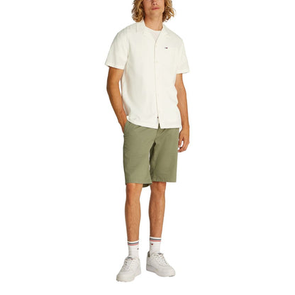 Man wearing Tommy Hilfiger Jeans Cream Cotton Shortsleeve Shirt and olive shorts, showcasing casual summer style.