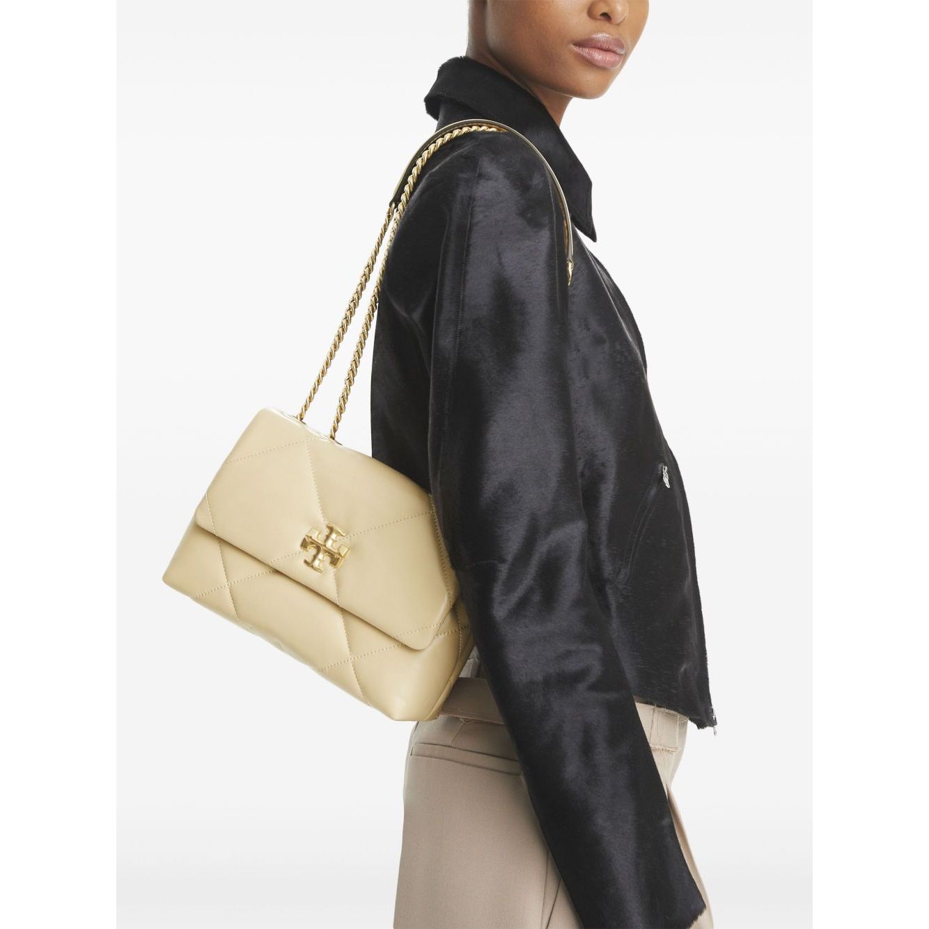 Tory Burch Kira Diamond small leather shoulder bag in light yellow, worn on shoulder with chain-link strap and gold-tone logo plaque.