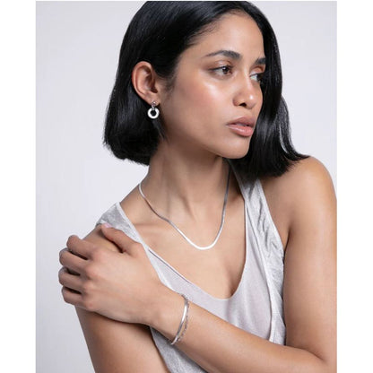 Woman wearing elegant silver jewelry set, including necklace and earrings, styled with a sleeveless top. Fashion and beauty concept.