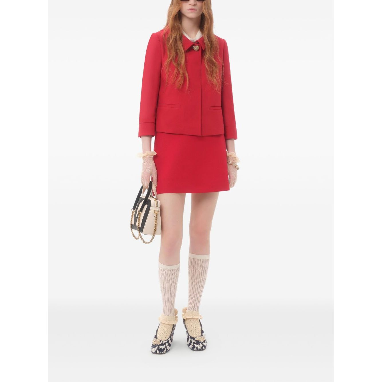 Model wearing Valentino Crepe Couture Skirt in red with heart motif, pocket detail, styled with jacket and chic accessories.