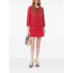 Model wearing Valentino Crepe Couture Skirt in red with heart motif, pocket detail, styled with jacket and chic accessories.