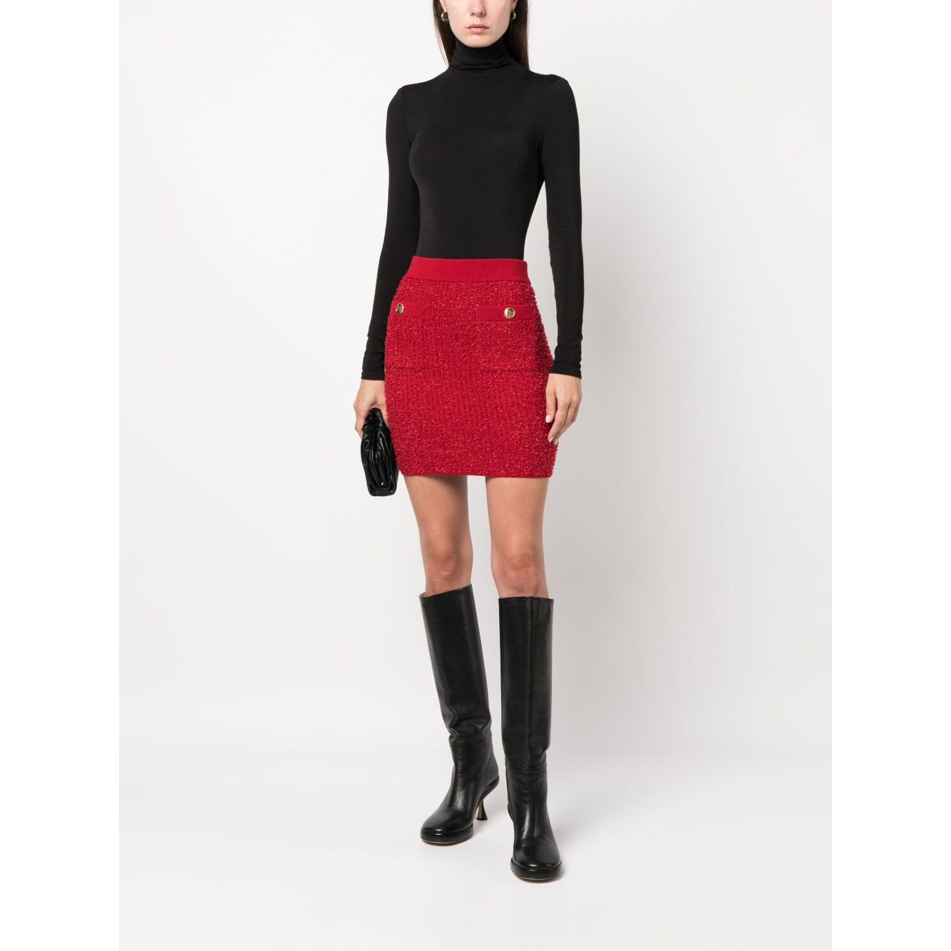 Model wearing Wolford Top Black, long sleeve roll neck bodysuit, paired with a red skirt, black boots, holding a small black clutch.