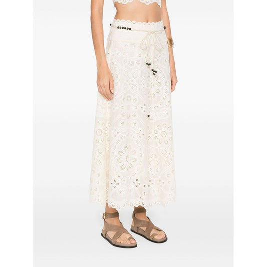 Woman wearing Zimmermann Skirts Ivory with beige front tie, cut-out floral detailing, and lettuce hem Rhiannon maxi skirt.